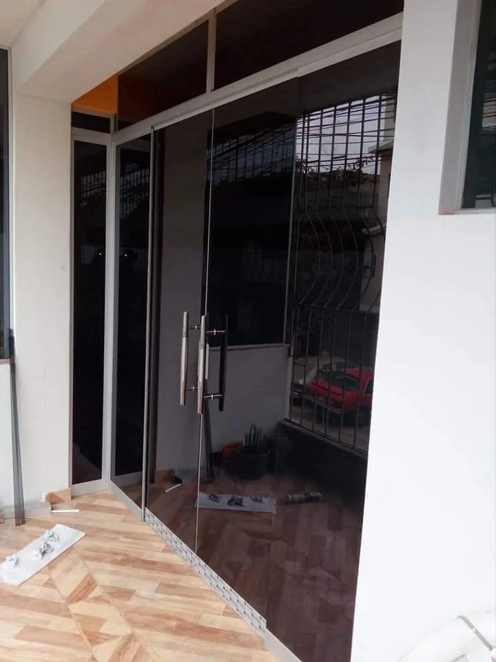 Mampara de aluminio natural con vidrio gris polarizado, lámina de seguridad y manija de acero inoxidable
