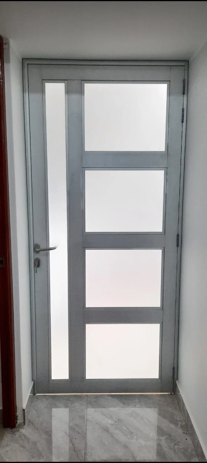 Puerta de aluminio natural con vidrios arenados de 6 mm con marco grueso